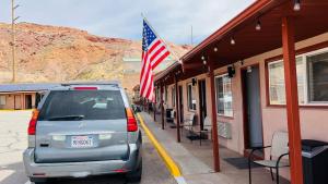 摩押的住宿－Inca Inn Moab，停在一座悬挂美国国旗的建筑旁边的面包车