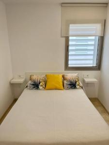 a bedroom with a bed with two pillows and a window at IDEAL ESTUDIO PARA PAREJAS in Conil de la Frontera