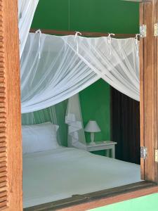 a bed with a canopy in a green bedroom at Pousada Loin de Tout in Corumbau
