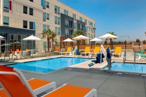 a hotel pool with chairs and a man standing next to it at Aloft Dublin-Pleasanton in Dublin