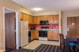 a kitchen with wooden cabinets and a white refrigerator at TownePlace Suites by Marriott Lafayette in Lafayette