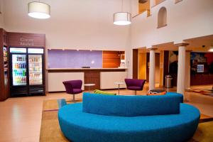 un gran vestíbulo con un sofá azul y sillas moradas en Fairfield Inn & Suites Modesto, en Modesto