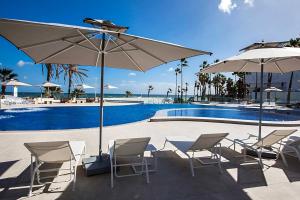 a group of chairs and umbrellas next to a pool at Sousse Pearl Marriott Resort & Spa in Sousse