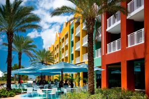 a hotel with blue umbrellas and tables and palm trees at Renaissance Wind Creek Curacao Resort in Willemstad