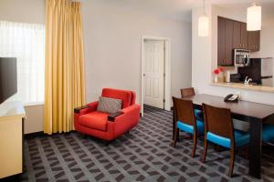 TownePlace Suites by Marriott Phoenix Goodyear في غوديير: غرفة معيشة مع كرسي احمر وطاولة طعام