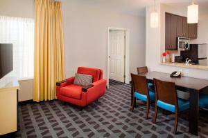 a living room with a red chair and a dining room table at TownePlace Suites by Marriott Phoenix Goodyear in Goodyear