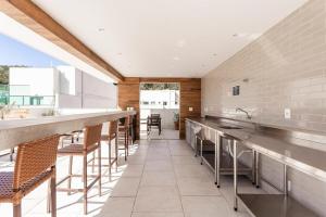 a large kitchen with a long bar with stools at Apto Itaipava, piscina borda infinita, montanha in Itaipava