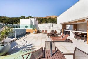 a patio with chairs and tables on a building at Apto Itaipava, piscina borda infinita, montanha in Itaipava