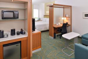 Habitación de hotel con cama y escritorio con TV. en SpringHill Suites by Marriott Raleigh Cary en Cary