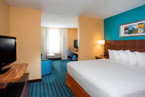 a hotel room with a bed and a flat screen tv at Fairfield Inn & Suites Oshkosh in Oshkosh