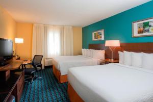 a hotel room with two beds and a television at Fairfield Inn & Suites Oshkosh in Oshkosh