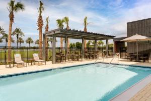 a swimming pool with tables and chairs and palm trees at Courtyard by Marriott Port St. Lucie Tradition in Cana