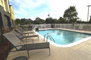 a swimming pool with chairs next to a building at Fairfield Inn & Suites Jackson Airport in Pearl