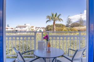 a table with a bottle of wine and flowers on a balcony at Sergiani Garden Hotel Apartments in Stalís