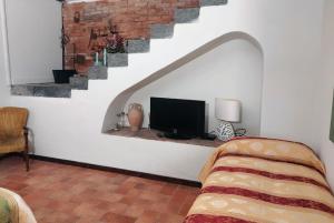 ein Wohnzimmer mit einem TV und einer Treppe in der Unterkunft Villa Alessio - Case Vacanza con Piscina sull'Etna in Puntalazzo