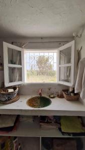 encimera de cocina con fregadero y ventana en Maison de vacance pour les amateurs de la nature, en Kelibia