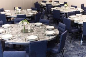 grupa stołów z niebieskimi krzesłami i talerzami w obiekcie Courtyard by Marriott Rapid City w mieście Rapid City