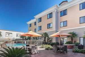 a hotel patio with tables and umbrellas and a pool at Courtyard Shreveport-Bossier City/Louisiana Boardwalk in Bossier City