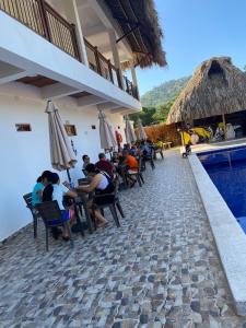 a group of people sitting at a restaurant next to a swimming pool at Hostal Grand Park Palomino in Palomino