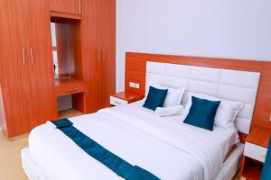 um quarto com uma grande cama branca com almofadas azuis em Luxe Furnished Apartments Unit 3 em Meru