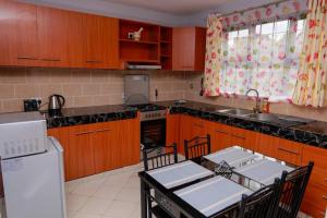 uma cozinha com armários de madeira e uma mesa com cadeiras em Luxe Furnished Apartments Unit 3 em Meru