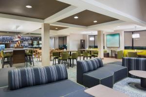 un hall avec des chaises et des tables ainsi qu'un bar dans l'établissement Courtyard by Marriott Springfield Airport, à Springfield