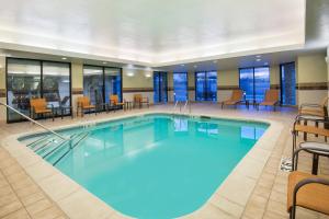 - une piscine dans une chambre d'hôtel avec des chaises et des tables dans l'établissement Courtyard by Marriott Springfield Airport, à Springfield
