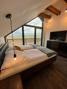 a bedroom with a large bed and a large window at Holiday Resort Šefec in Liptovská Sielnica