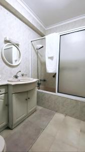 ein Bad mit einem Waschbecken und einer Dusche mit einem Spiegel in der Unterkunft Ocean and River Apartment in Torreira