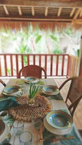una mesa con platos y vasos y una planta en ella en villa gilimakyah en Gili Air