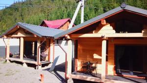 eine Holzhütte mit einer Veranda und einem Dach in der Unterkunft Hotel Berloga-Sinevir in Synewyrska Poljana