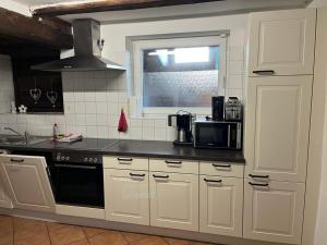 a kitchen with white cabinets and a black counter top at Romantisches Schwarzwaldhaus in Äule