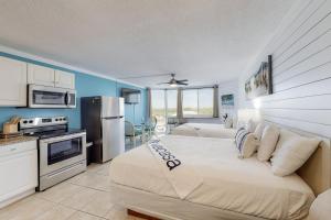 a bedroom with two beds and a kitchen with a stove at Top of the Gulf 702 Teal Waters in Panama City Beach