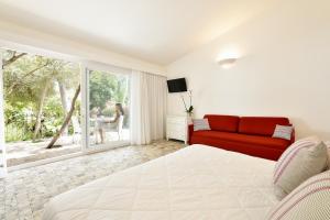 a bedroom with a bed and a red couch at Arbatax Park Resort - Cottage in Àrbatax