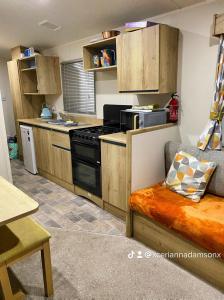 a kitchen with wooden cabinets and a stove top oven at Presthaven Sands in Prestatyn