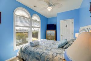 a blue bedroom with a bed and a window at Waterfront Emerald Isle Home with Dock Access! in Emerald Isle