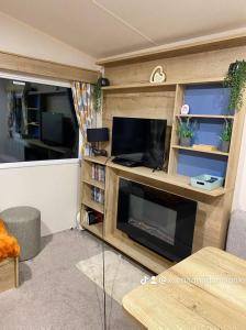 a living room with a fireplace and a tv at Presthaven Sands in Prestatyn