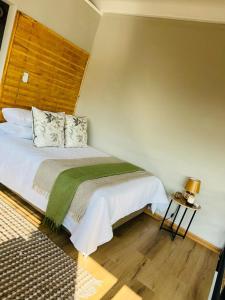 1 dormitorio con 1 cama con manta verde y blanca en Bird Nest Lodge, en Durban