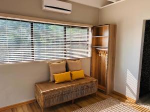 duas almofadas amarelas sentadas num banco numa sala com janelas em Bird Nest Lodge em Durban
