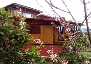 una pequeña casa de madera con flores rosas delante de ella en Holo Pousada Vale Encantado, en Rancho Queimado