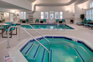 a pool in a building with chairs and tables at Residence Inn by Marriott Richmond Chester in Woodvale