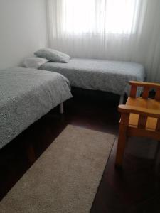 Zimmer mit 3 Betten und einem Holzstuhl in der Unterkunft O PISIÑO in Cambados