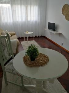ein Wohnzimmer mit einem weißen Tisch und einem Sofa in der Unterkunft O PISIÑO in Cambados