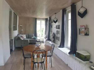ein Wohnzimmer mit einem Tisch, Stühlen und einem Sofa in der Unterkunft Logement à 30min de la défense avec piscine privative in Conflans-Sainte-Honorine