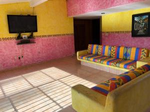 ein Wohnzimmer mit einem Sofa und einem Flachbild-TV in der Unterkunft Hermosa Casa Ikal en Acapulco in Barra de Coyuca