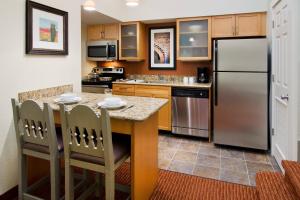 Il comprend une cuisine équipée d'un réfrigérateur et d'une table avec des chaises. dans l'établissement Residence Inn Santa Fe, à Santa Fe