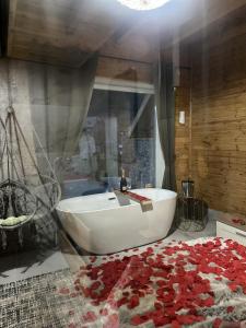 a bathroom with a white tub and red roses on the floor at Bujtina Miqesia in Theth