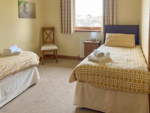 a bedroom with two beds and a window and a chair at Sandy Beach in Nairn