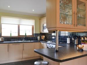 a kitchen with wooden cabinets and a black counter top at Sandy Beach in Nairn