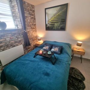 a bedroom with a blue bed with a table on it at Studio de 23 m² au centre de Montfort L'amaury in Méré